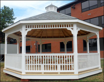 20 Vinyl Octagon Gazebo shown with a treated pine deck, 1x1 standard railings, standard braces, cupola, top railing sections, old english pewter asphalt shingles 4 bench sections, and two 6 Red Cedar Picnic Tables w/ Benches