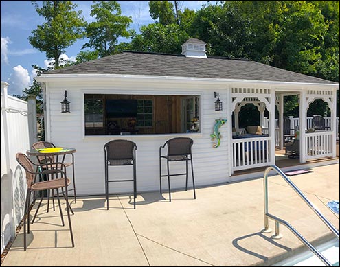 12 x 24 Vinyl Pool House shown with White Siding and Trim, Brown Composite Decking, Driftwood Asphalt Shingles, Cupola, and Concession Window with Bar. Lighting supplied by customer.